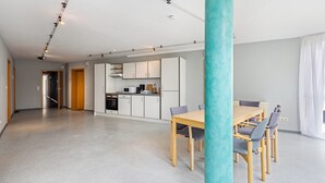 A modern kitchen with white cabinets and a dining area with a wooden table and chairs. - Apartment 'Zwei Betten Studio' with Wi-Fi (Lübeck)
