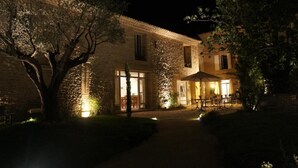 A stone building with a patio area, large windows, and a tree in the foreground.