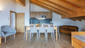 A modern loft with exposed wooden beams, a kitchen with a microwave, and a dining area with a table and chairs. - T-Resort by Interhome (La Tzoumaz)