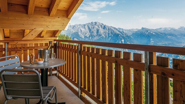 A wooden deck with a table and chairs, overlooking a mountainous landscape. - T-Resort by Interhome (La Tzoumaz)