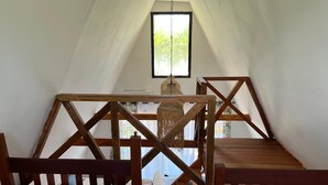 A cozy room with a wooden table, a hanging light fixture, and a window with a view of greenery. - FAMILY BUNGALOW: E-FRAME HOUSE Facing the Ocean (Toamasina)