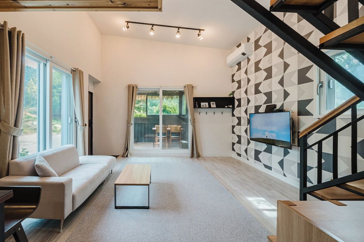 Una sala de estar moderna con un sofá, una mesa de centro, un televisor y una escalera.