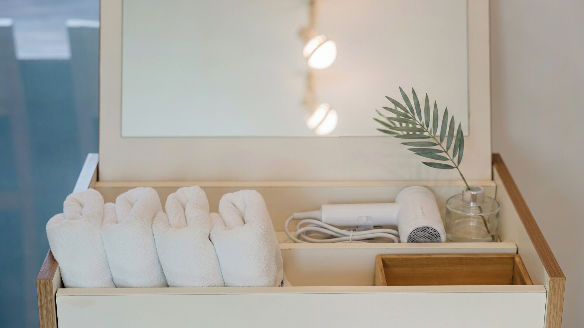 A wooden box with towels, a hairdryer, and a plant.