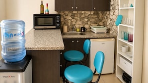 A compact kitchen with a water dispenser, microwave, sink, and a small refrigerator.