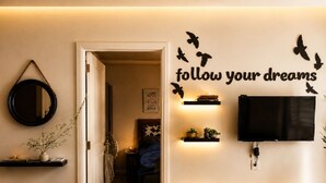 A room with a mirror, a wall-mounted TV, and a motivational quote.