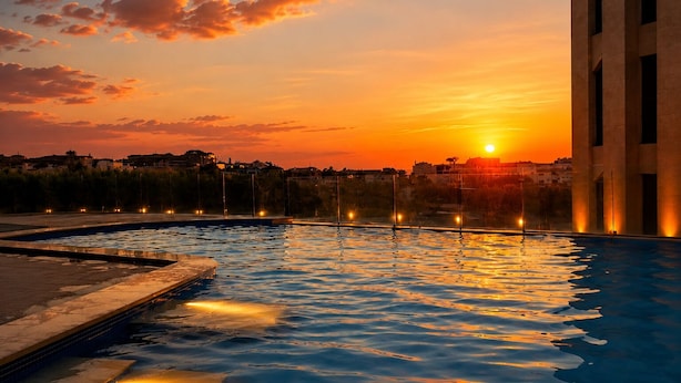 A swimming pool with a sunset view, a building with vertical lines, and a distant cityscape.