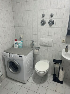Ein kleines Badezimmer mit Waschmaschine, Toilette und Waschbecken.