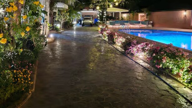A nighttime pathway leading to a pool area with a car parked in the background.