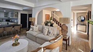 Ein modernes Wohnzimmer mit Sofa, Couchtisch und Essbereich mit Stühlen.