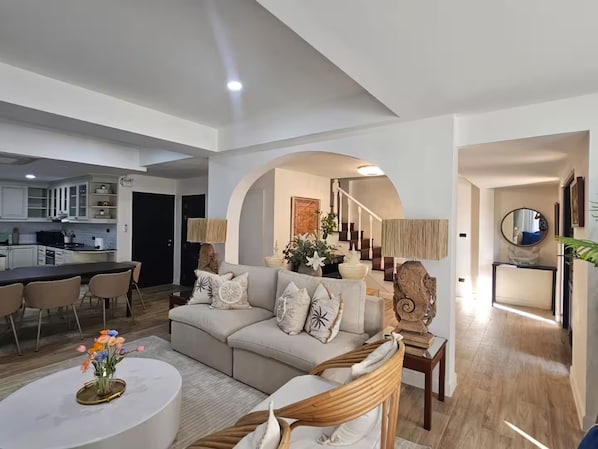 Ein modernes Wohnzimmer mit Sofa, Couchtisch und Essbereich mit Stühlen.