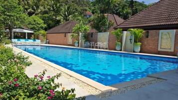 Una piscina al aire libre, sillones reclinables de piscina