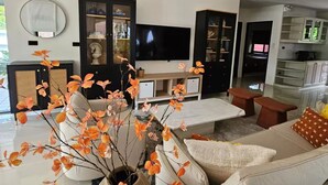 A modern living room with a sofa, coffee table, and a TV. There is a kitchen area in the background.