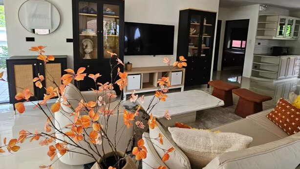 Ein modernes Wohnzimmer mit Sofa, Couchtisch und Fernseher. Im Hintergrund ist eine Küchenzeile erkennbar.