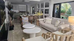 A modern living room with a sofa, two round tables, and wicker chairs.
