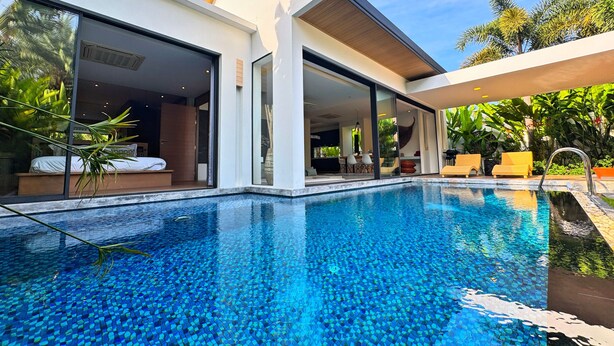 A modern house with a swimming pool, large glass doors, and outdoor furniture. - Blue Coral Luxury Villa  (Tambon Sa Khu)