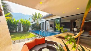 A modern outdoor living area with a pool, seating, and a view of mountains. - Blue Coral Luxury Villa  (Tambon Sa Khu)
