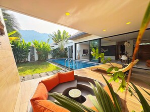 A modern outdoor living area with a pool, seating, and a view of mountains. - Blue Coral Luxury Villa  (Tambon Sa Khu)