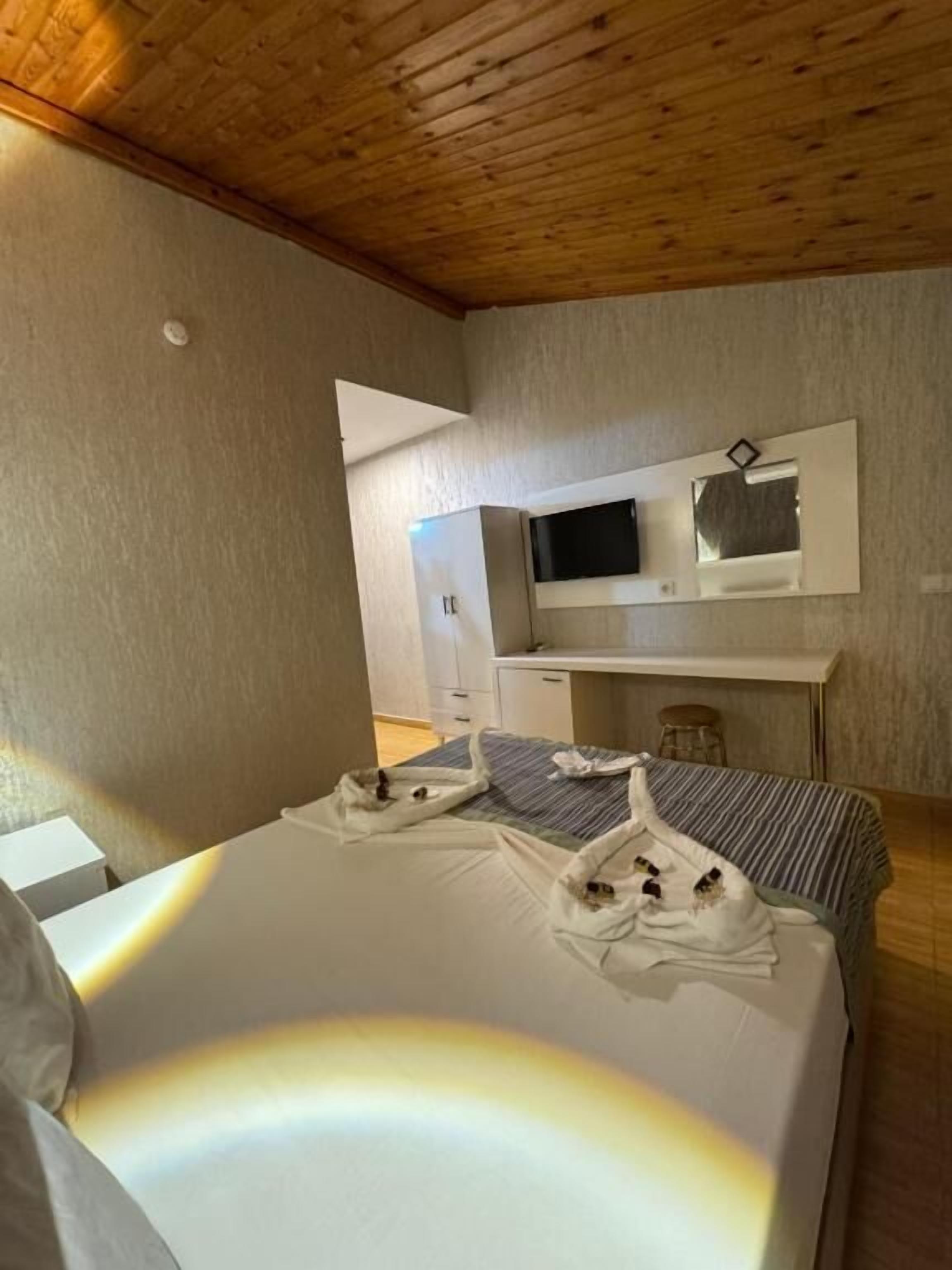 A hotel room with a bed, a TV mounted on the wall, a desk, and a chair.