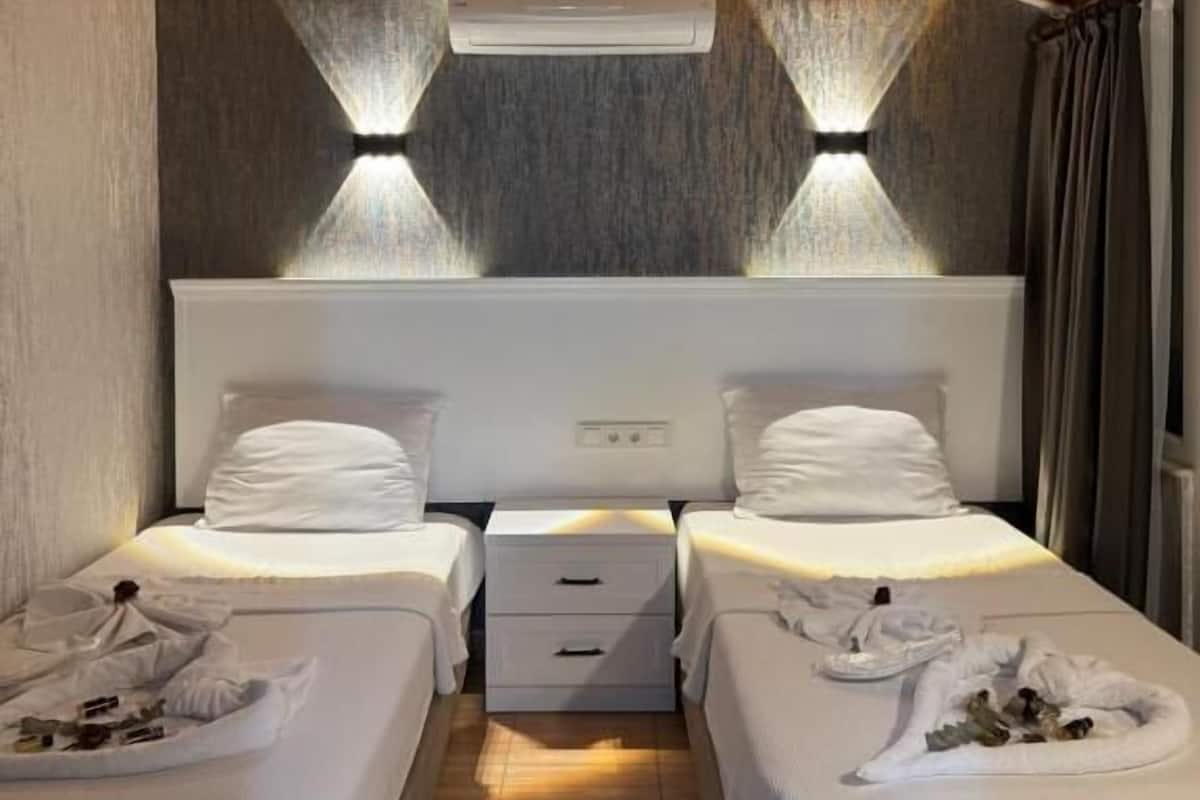 Habitación de hotel con dos camas, techo de madera y aire acondicionado de pared.