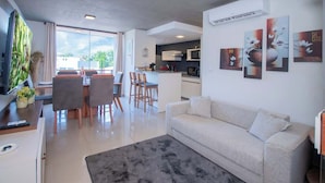 A modern living room with a sofa, a dining area with chairs, a kitchen in the background, and artwork on the walls. - Corporate Stays Insignia Fly (Luque)