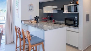 A compact kitchen with a central island, bar stools, a microwave, and a coffee maker. - Corporate Stays Insignia Fly (Luque)