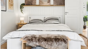Una camera da letto con un letto, un comodino con una lampada, una coperta di pelliccia e decorazioni alle pareti.
