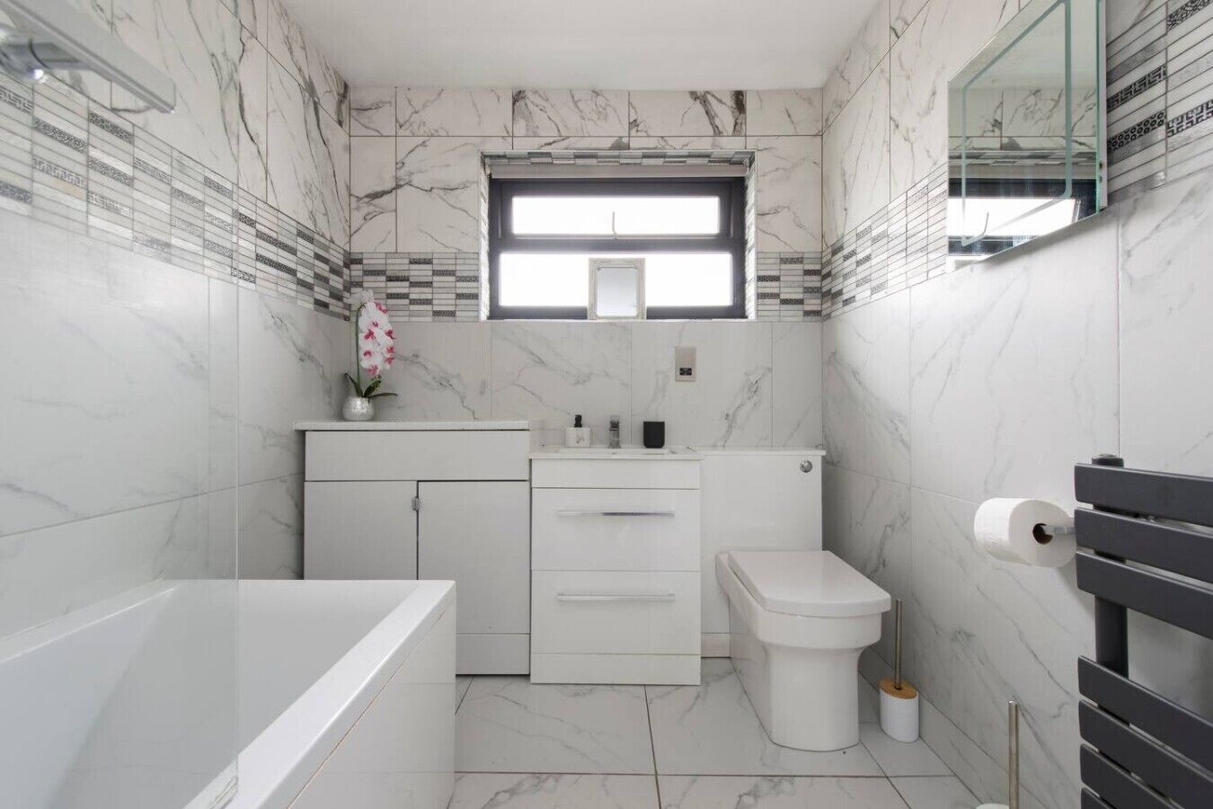 A modern bathroom with a bathtub, toilet, and vanity.