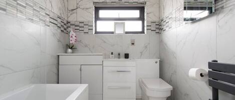 A modern bathroom with a bathtub, toilet, and vanity.