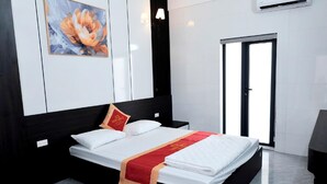 Un lit bien fait, recouvert d ’une courtepointe rouge et blanche, avec un oreiller orné d’un logo rouge et un tableau représentant une fleur accroché au mur.