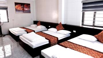 Habitación de hotel con tres camas, un ventanal grande, aire acondicionado de pared y un cuadro.