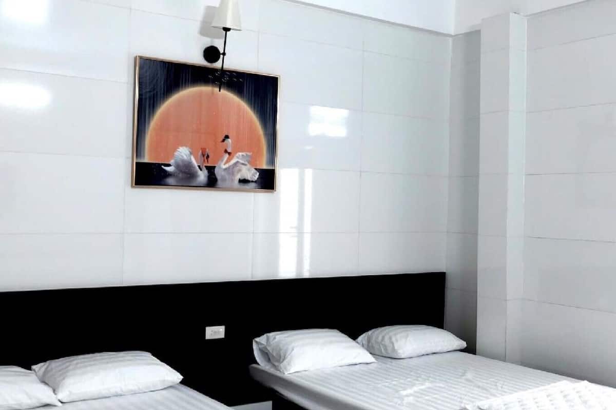 A hotel room with two beds, a large painting on the wall, and a modern design.