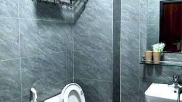 Ein Badezimmer mit Toilette, Dusche, Waschbecken und Spiegel.