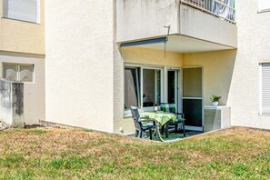 A residential building with a covered patio area featuring a table and chairs, a small refrigerator, and a potted plant. - Apartment 'Am Hafen' with Lake View, Private Terrace, and Wi-Fi (Konstanz)
