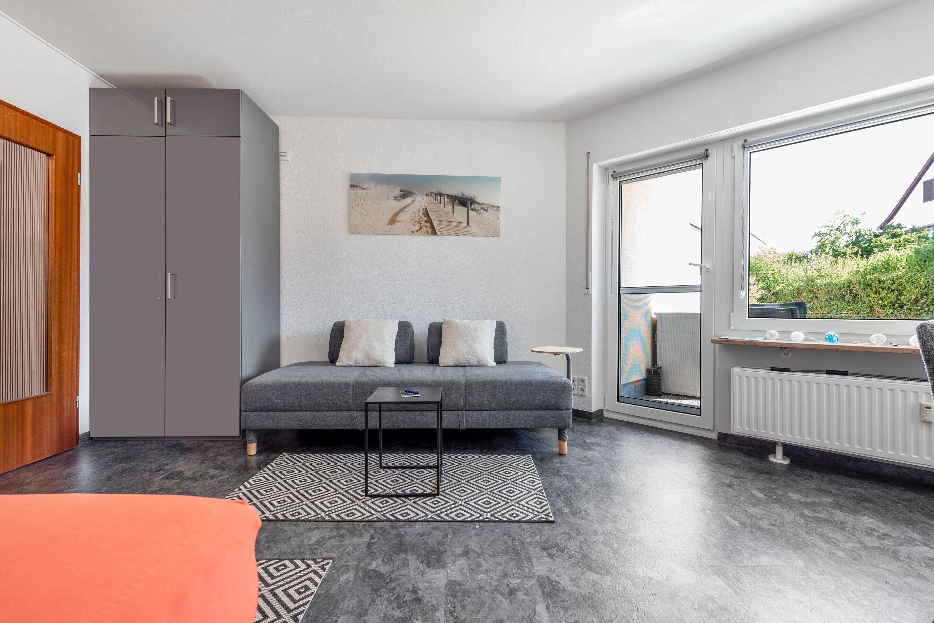 Un soggiorno moderno con un divano grigio, un piccolo tavolino nero e un tappeto decorato.