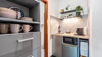 Eine kleine Küche mit Backofen, Kaffeemaschine und Spüle.