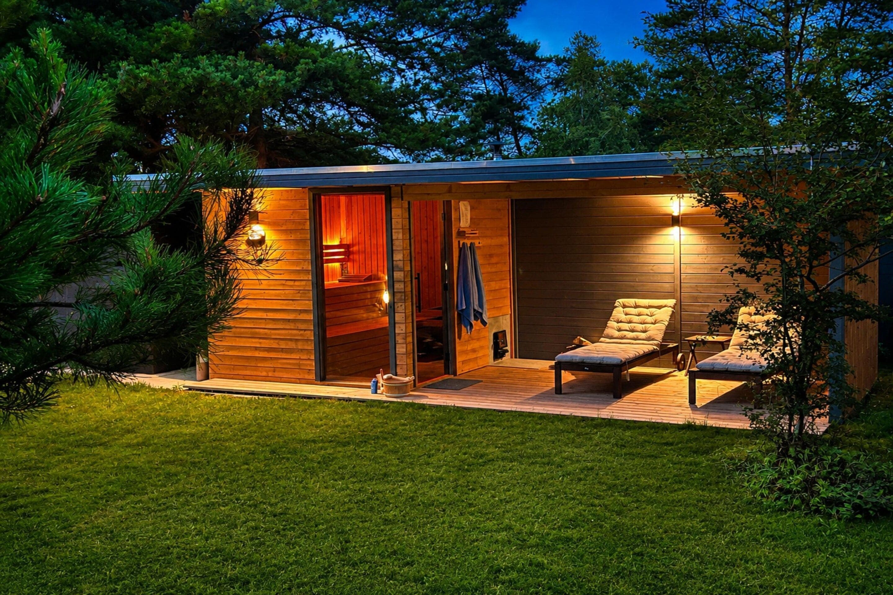 A wooden cabin with a deck, two lounge chairs, and a sauna.