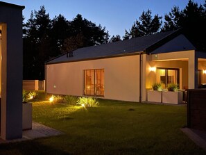 A modern house with a well-maintained lawn, a large window, and a small porch area. - Large Holiday Home, Swimming Pool, Sauna, Jacuzzi (Krokowa)