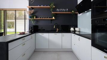 A modern kitchen with white cabinetry, a black countertop, and a built-in oven.