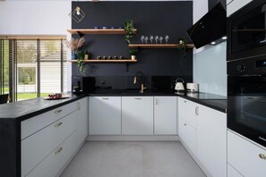 Una cocina moderna con armarios blancos, encimera negra y horno empotrado.