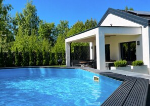 A modern pool area with a covered patio, surrounded by lush greenery. - Large Holiday Home, Swimming Pool, Sauna, Jacuzzi (Krokowa)