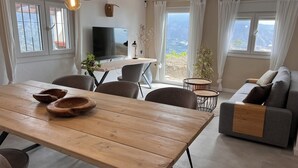 A modern living room with a wooden dining table, grey sofa, and a TV. - Villa Melin - Panoramic Views, Privacy, and a Heated Pool (Torrox)
