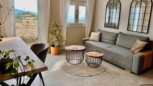 A living room with a sofa, two round tables, a potted plant, and a view of the outdoors. - Villa Melin - Panoramic Views, Privacy, and a Heated Pool (Torrox)