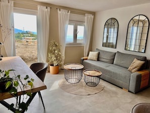 A living room with a sofa, two round tables, a potted plant, and a view of the outdoors. - Villa Melin - Panoramic Views, Privacy, and a Heated Pool (Torrox)