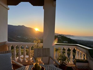 A balcony with a view of the sunset over a coastal landscape, including mountains and a body of water. - Villa Melin - Panoramic Views, Privacy, and a Heated Pool (Torrox)