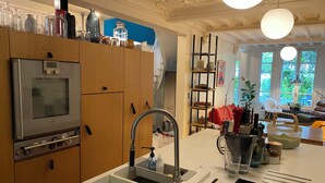 A kitchen with a stainless steel oven, a sink, wooden cabinets, and a window with a view of greenery. - Family home just a stone's throw from Paris, with a garden and a hammam (Asnières-sur-Seine)