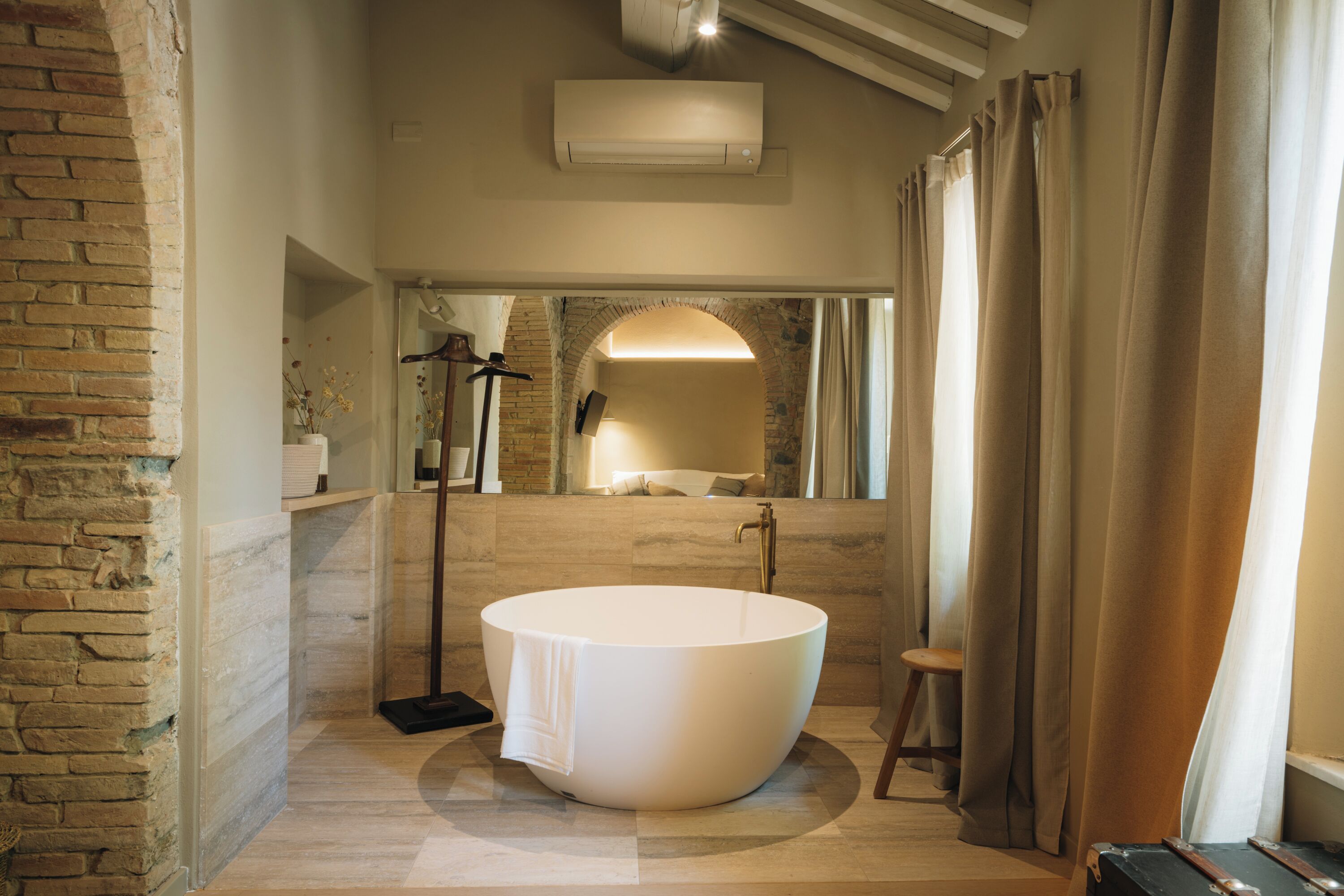 A modern bathroom with a freestanding bathtub, a mirror, and a shower area.