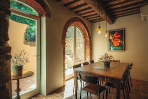 A rustic dining area with a wooden table, chairs, and a potted plant. - Palazzo Lucchini (Montalcino)