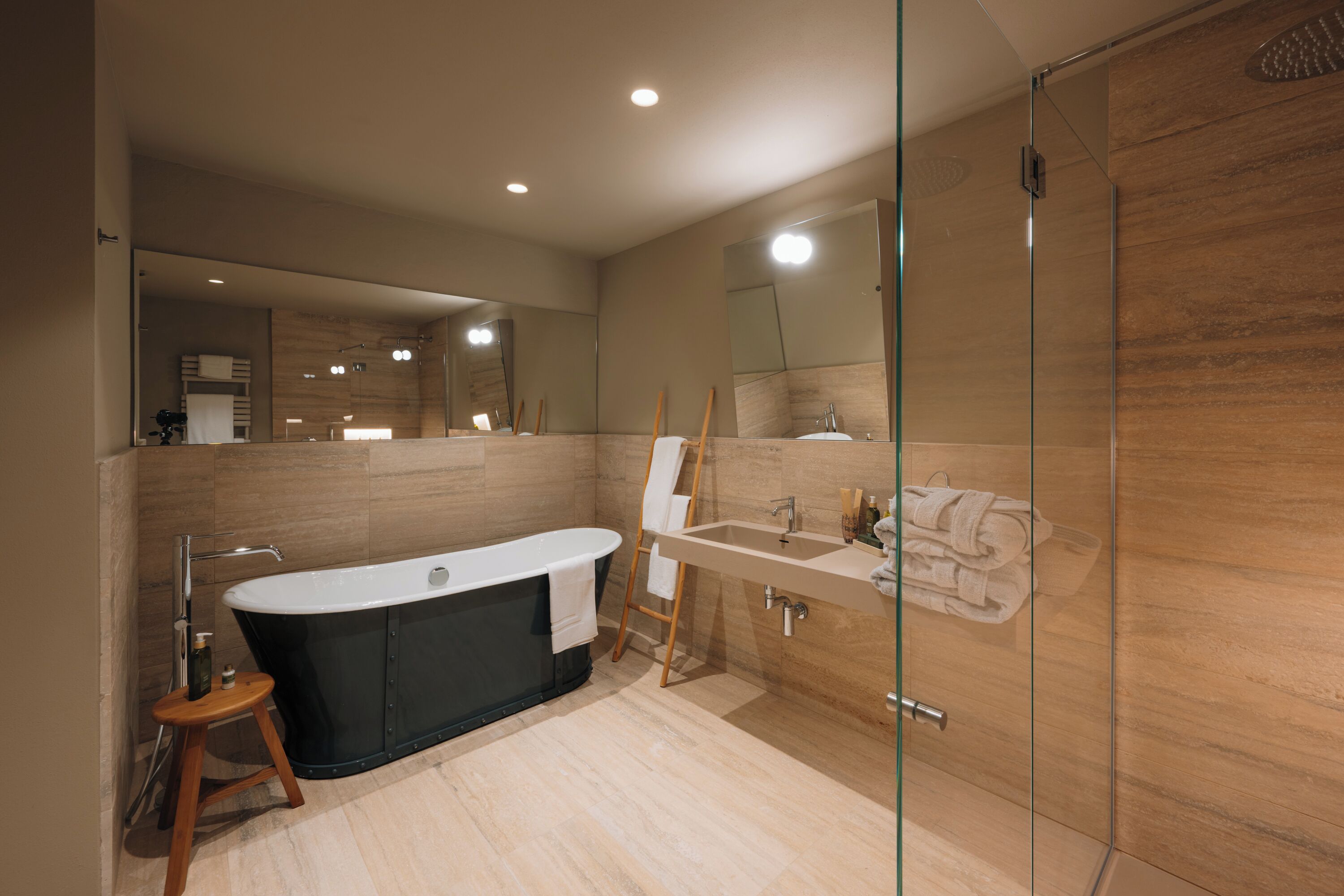 Un baño moderno con una bañera independiente, ducha con cerramiento de vidrio y tocador con lavamanos y espejo.