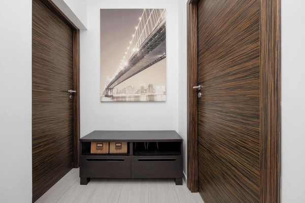 A hallway with wooden doors, a small bench, and a decorative wall picture. The bright interior has a clean and modern design.
