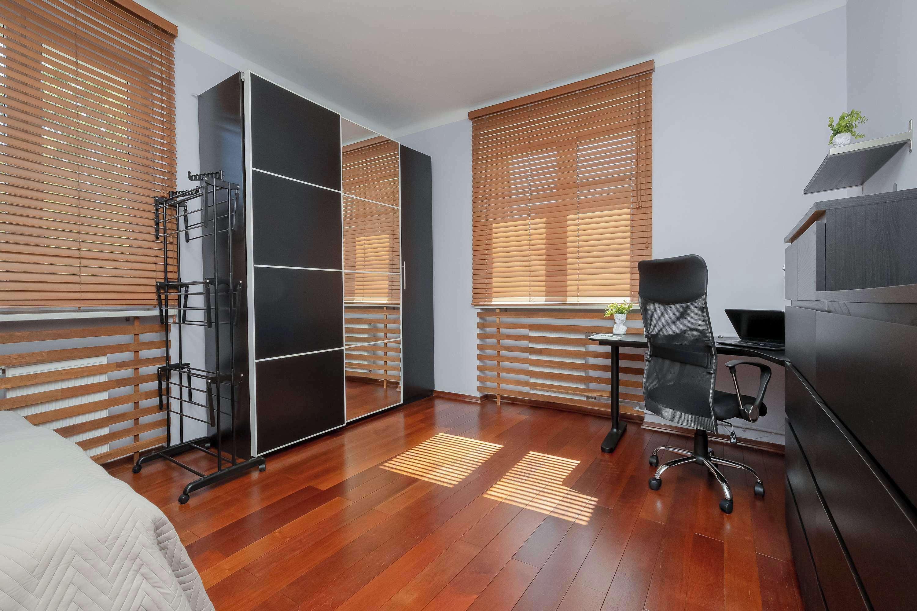A modern bedroom with a bed, a desk, a chair, and a wardrobe.
